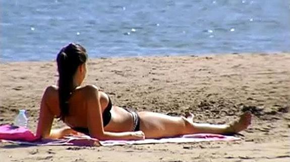 Una mujer, tomando el sol en la playa de la Malvarrosa en pleno otoño.