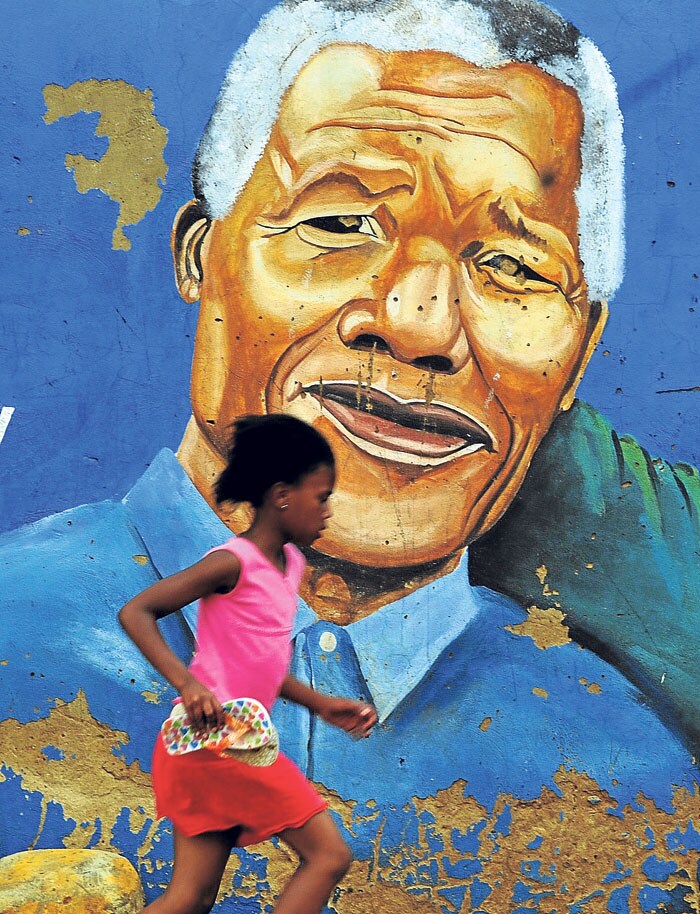 Una niña corre delante de un mural de Mandela en Soweto.