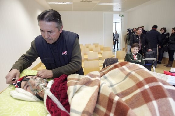 El padre de Alfredo prepara la cama medicalizada en la sala donde se celebró ayer el juicio junto. :: dani madrigal
