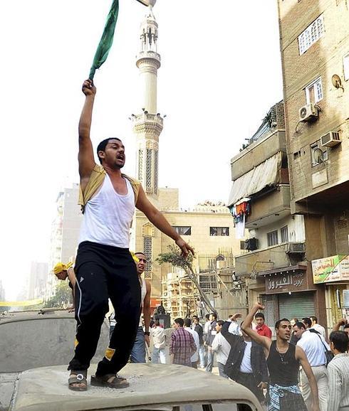 Un cristiano copto protesta subido a lo alto de un coche en el Cairo.