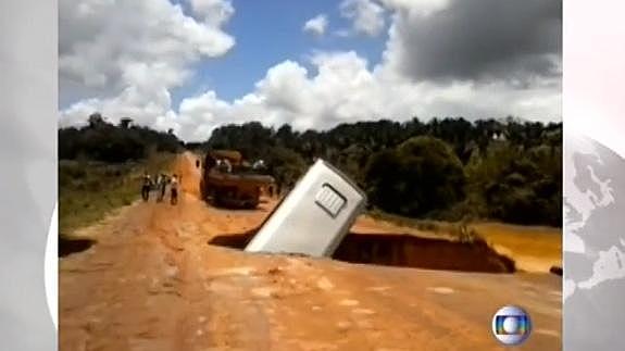 Un autobús cae en un cráter formado por las lluvias