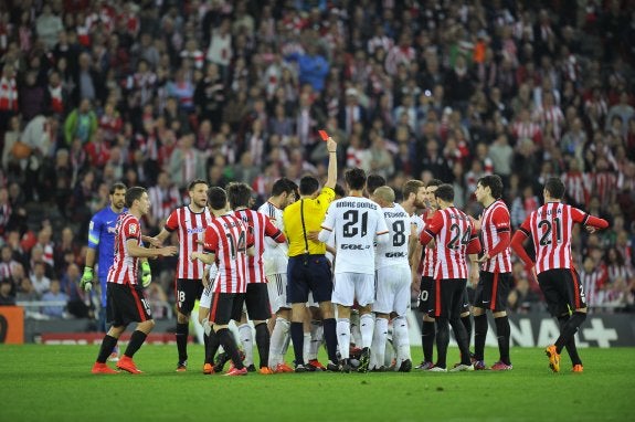 Teixeira enseña la roja a Otamendi, mientras el argentino está en el suelo rodeado de jugadores. :: ignacio pérez