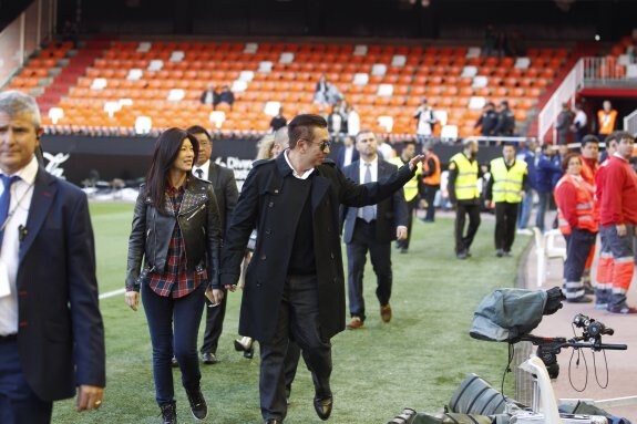 Peter Lim, acompañado de su mujer, saluda a los aficionados que estaban en la tribuna antes del partido. 