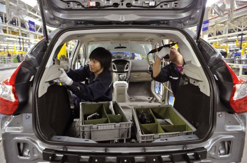 Dos operarios chinos ultiman el interior de un coche en la factoría de Ford en Chongqing.:: Reuters