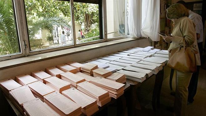 Varias personas eligen las papeletas para elegir alcaldes y diputados autonómicos.