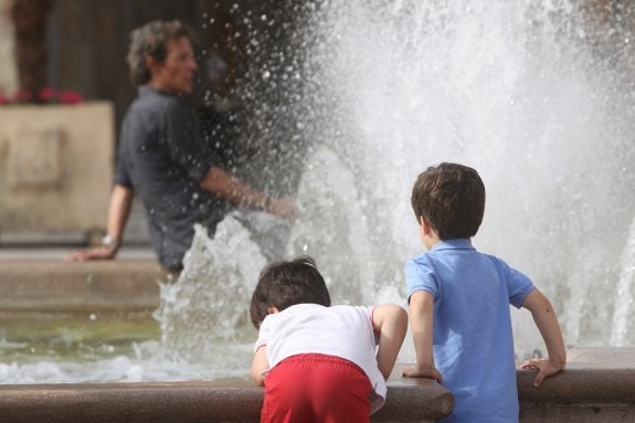 Un par de niños en la fuente situada en la Plaza de la Virgen de Valencia. :: J.MONTAÑANA