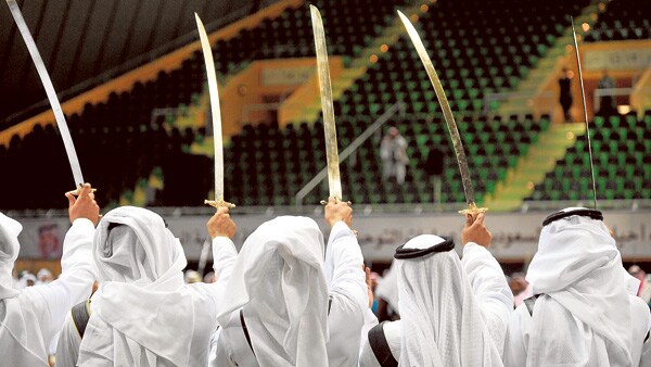 Miembros de un grupo saudí de danzas tradicionales esgrimen sus sables en una actuación.