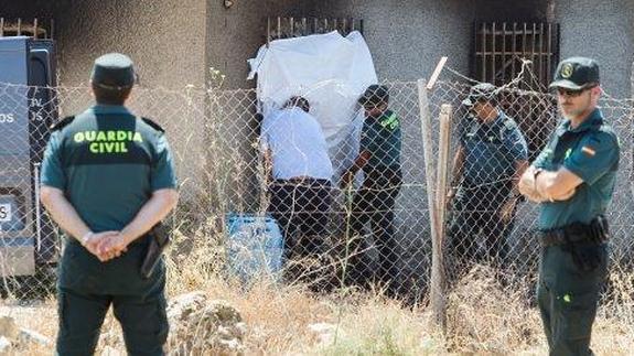 Guardias civiles inspeccionan los alrededores de la casa de campo en la que aparecieron los cuerpos.