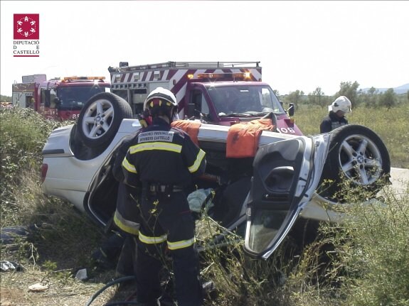 Dos bomberos junto al BMW 320 volcado. :: bomberos de castellón 