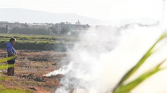 Un agricultor quemando paja en un arrozal.