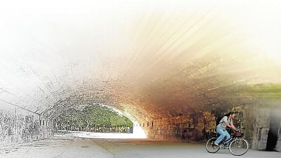 Un ciclista pasa por debajo del puente del Real, en el viejo cauce.