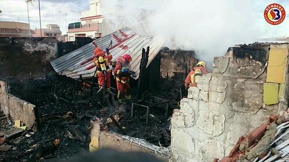 Los bomberos trabajando en la vivienda incendiada.