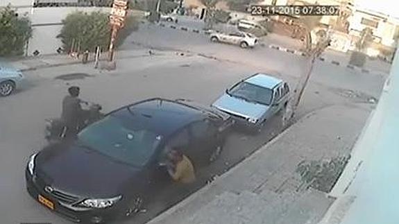 Un hombre forzando un espejo retrovisor de un coche.