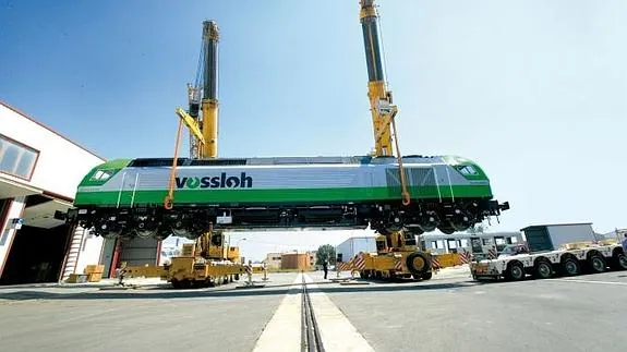 Dos grúas cargan una locomotora de Vossloh España para su transporte por carretera.