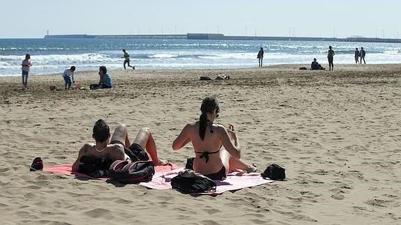 Una pareja toma el sol en la playa de Las Arenas. 