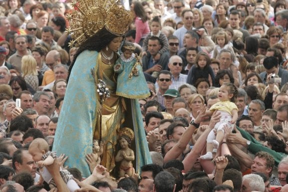 El público lleva en volandas a una niña para que toque el manto de la Virgen.  :: damián torres