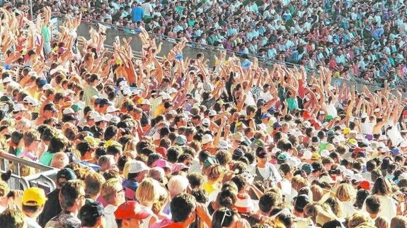 Cientos de personas hacen la ola durante un evento deportivo.