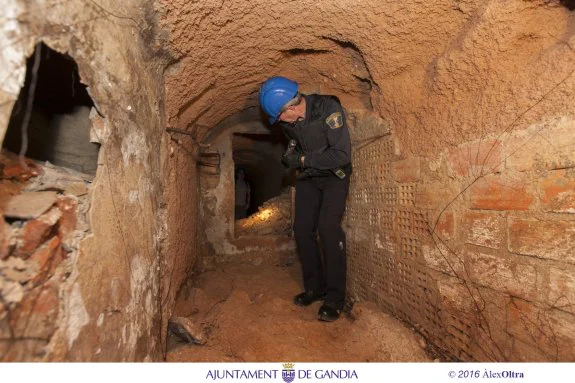 El jefe de la Policía Local observa el pasadizo que ha salido a la luz en los sótanos del ayuntamiento de Gandia. :: ÀLEX OLTRA