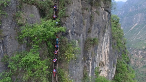 Los colegiales suben por la escalera de madera con sus mochilas a la espalda de vuelta a sus hogares tras la jornada escolar. :: chen jie