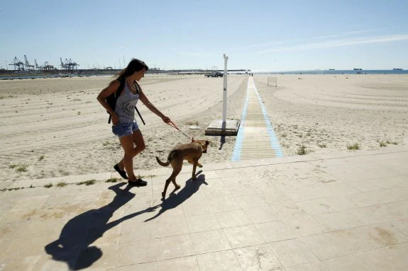 Una joven se dirige a la zona acotada para perros en la playa de Pinedo. :: irene marsilla