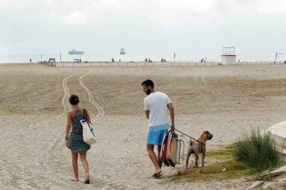 Bañistas con una mascota, antes de llegar a la zona acotada para perros de Pinedo. :: irene marsilla