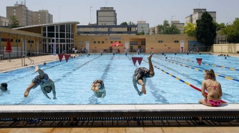 Dos bañistas se lanzan al agua en una piscina municipal.