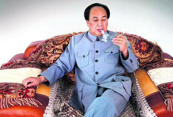 Zhenlong, en su casa, se fuma un cigarrillo como lo hacía Mao. El empresario sólo necesita un poco de arcilla para imitar su característica verruga. :: zigor aldama