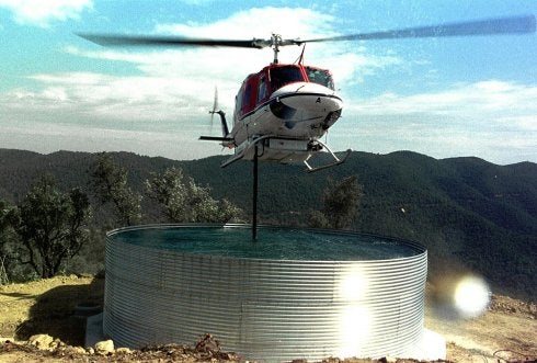 Un helicóptero recarga agua en un depósito. :: efe