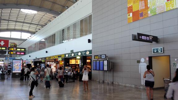 Zona comercual y unos baños en el aeropuerto de Alicante-Elche.