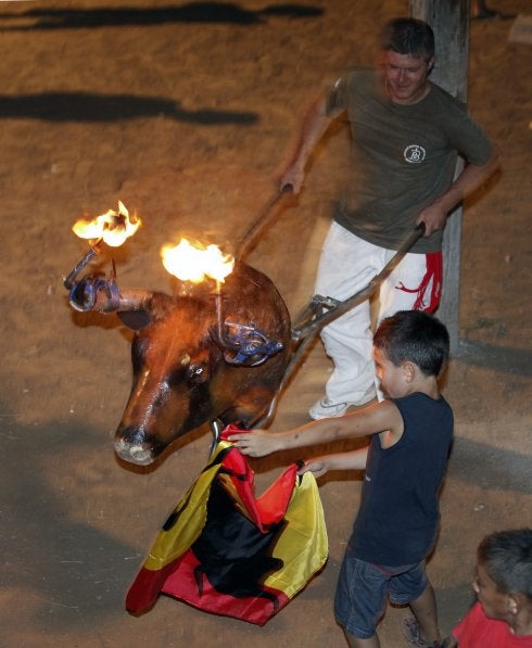 Un niño torea al paso de un carretón en unos festejos.