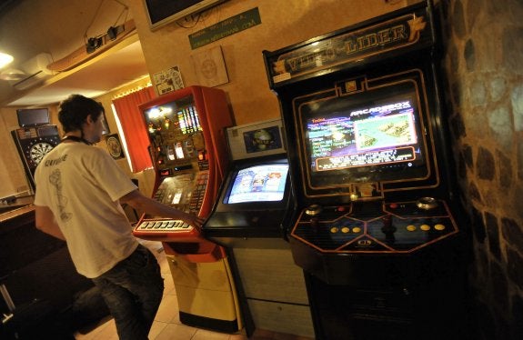 Un joven juega en una máquina tragaperras de un bar. 