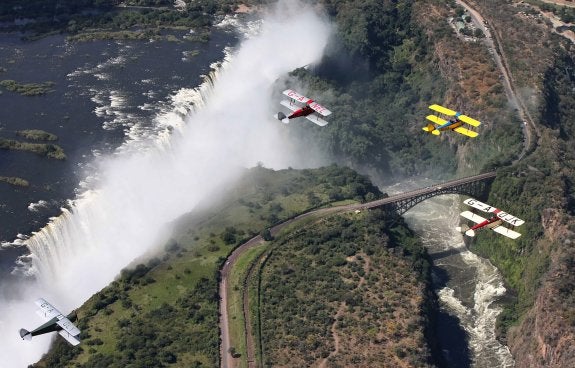 Tres biplanos Tiger Moth sobrevuelan  las cataratas Victoria, en Zimbabue,  durante uno de los rallies aéreos  celebrados sobre territorio africano.  :: vintage air rally