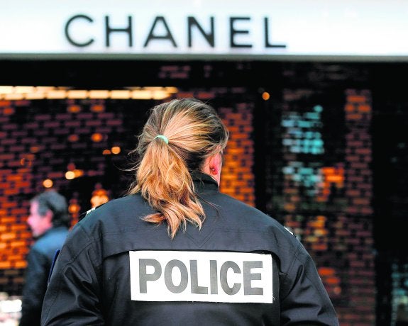 Una agente monta guardia ante una tienda de lujo asaltada en París.  ::  reuters