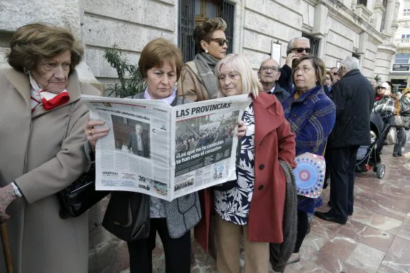 Personas en la cola del Ayuntamiento, leyendo LAS PROVINCIAS.