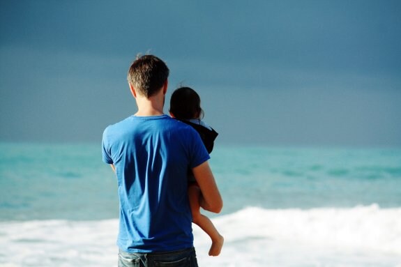 Un hombre sostiene a una menor en brazos a la orilla del mar. :: steven van Loy