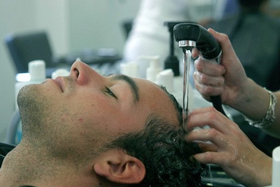 Un cliente se lava el cabello en una peluquería. :: Noelia Martínez