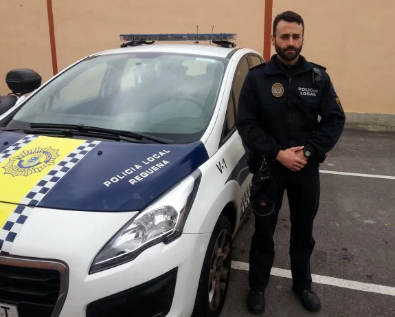 El oficial David García, junto a un coche patrulla de la Policía Local de Requena. :: lp