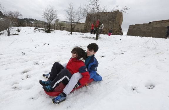 Dos niños se tiran por la nieve con un trineo ayer en Siete Aguas. :: jesús signes