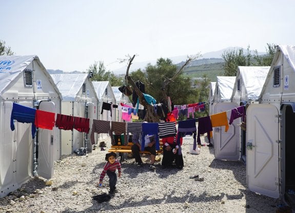 Una niña juega entre varios refugios de la Fundación Ikea en un campamento de Lesbos. Abajo, interior de un bungaló. :: Better Shelter