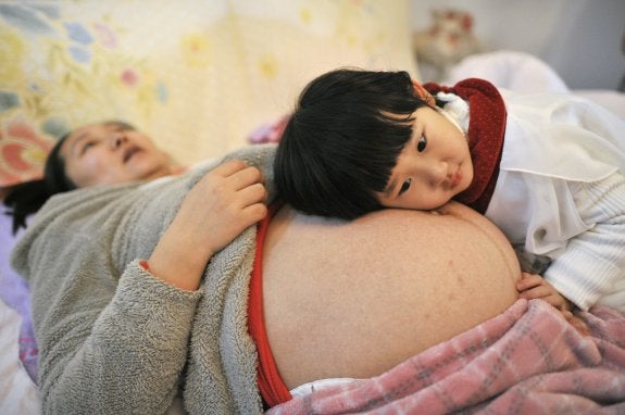 La familia de Li Yan, una china que espera su segundo hijo, aplica el oído a su abdomen para tratar de percibir a su futuro hermanito.