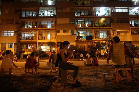 Una joven navega por internet en su móvil en una zona wifi del centro de La Habana. :: ALEXANDRE MENEGHINI / reuters