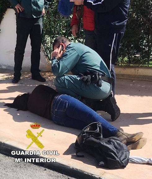 Agente de la Guardia Civil auxilia a la mujer en Burriana.