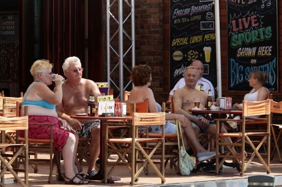 Turistas ingleses disfrutan de sus cervezas en una terraza de Benidorm. :: álex domínguezFurgoneta de 'recolectores' a la caza de turistas ingleses. :: r. c.