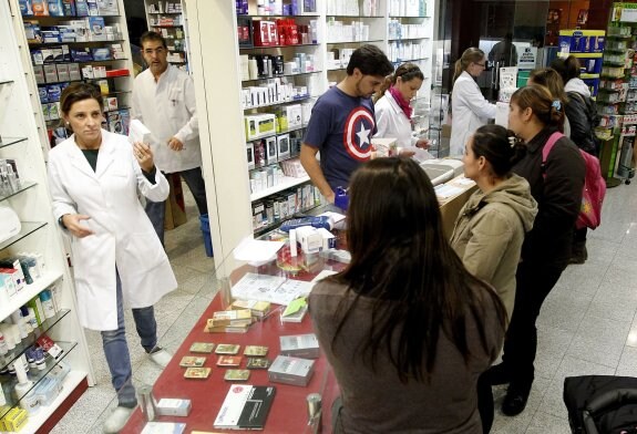 Profesionales y clientes en una farmacia valenciana. :: Jesús Signes