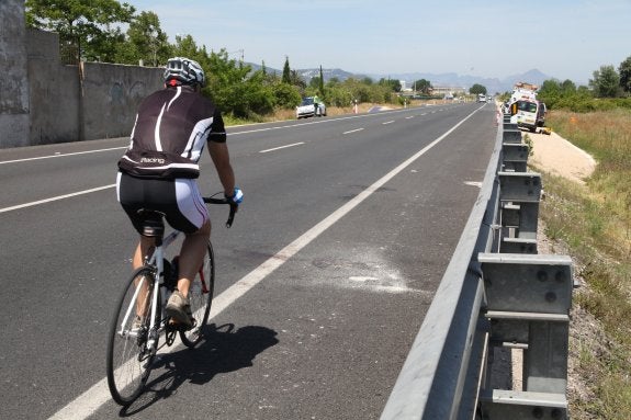 Un ciclista pasa por el lugar donde tuvo lugar el accidente donde murieron dos compañeros, en la nacional 332, en Oliva. :: Tino Calvo