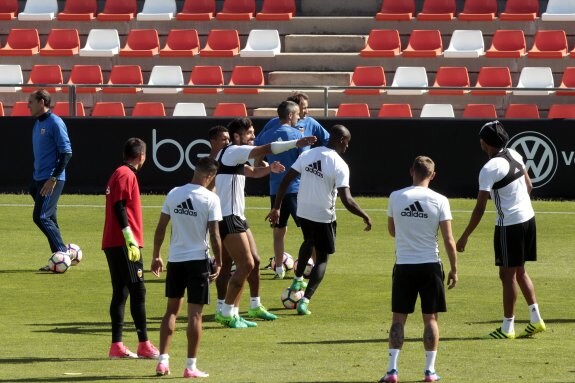  Los futbolistas del Valencia, al inicio del entrenamiento de ayer en Paterna con Voro al fondo . 
