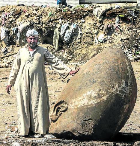 Un cairota posa junto a la colosal cabeza de un faraón, rescatada hace un poco más de dos meses por arqueólogos en Matariya, un populoso barrio de la capital.