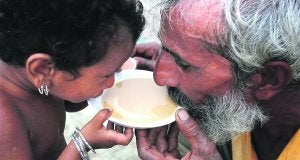 Un niño y un hombre comparten una taza de té en el campo de refugiados de Sukkur. ::
REUTERS