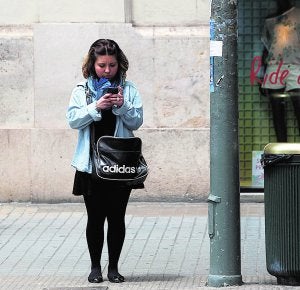 Una joven consulta su teléfono justo antes de cruzar un paso de cebra. ::                             IRENE MARSILLA