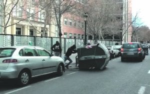 Dos encapuchados vuelcan un contenedor durante las protestas estudiantiles en Valencia. ::                             LP